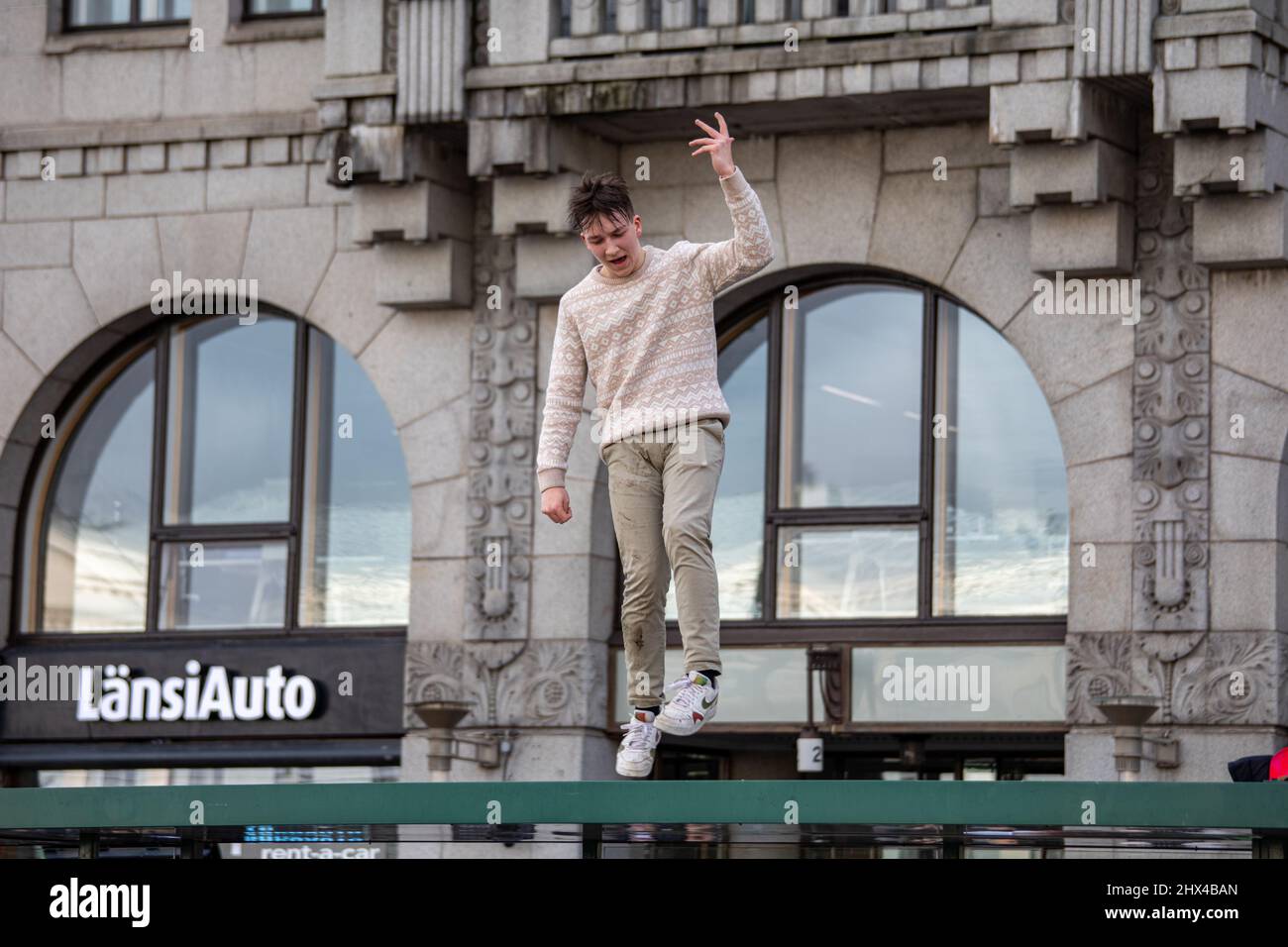 Young man dancing on tram stop shelter roof in celebration of Finnish ice hockey team's Olympic gold medal in Helsinki, Finland Stock Photo