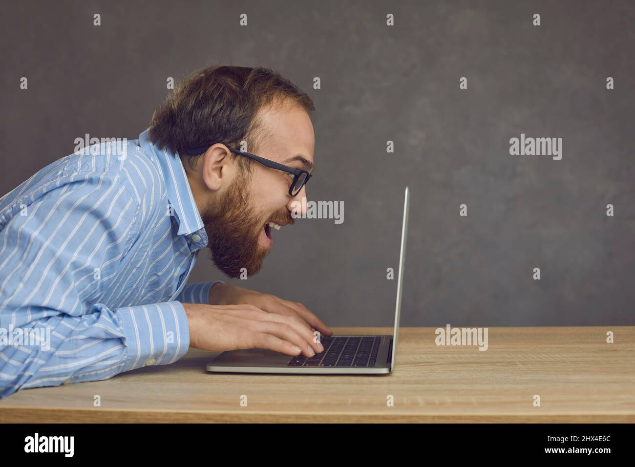 Funny caucasian man typing fast on laptop keyboard playing video game in  studio Stock Photo - Alamy