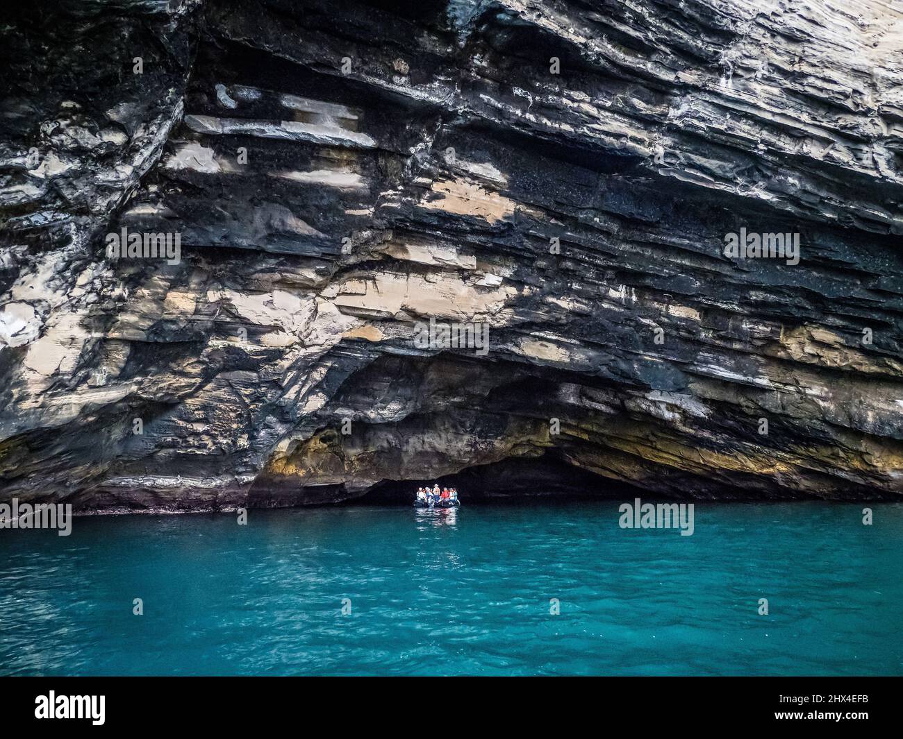 Tourists in a rubber Zodiac tour the cliffs of Isla Isabela, Galapagos, Ecuador Stock Photo