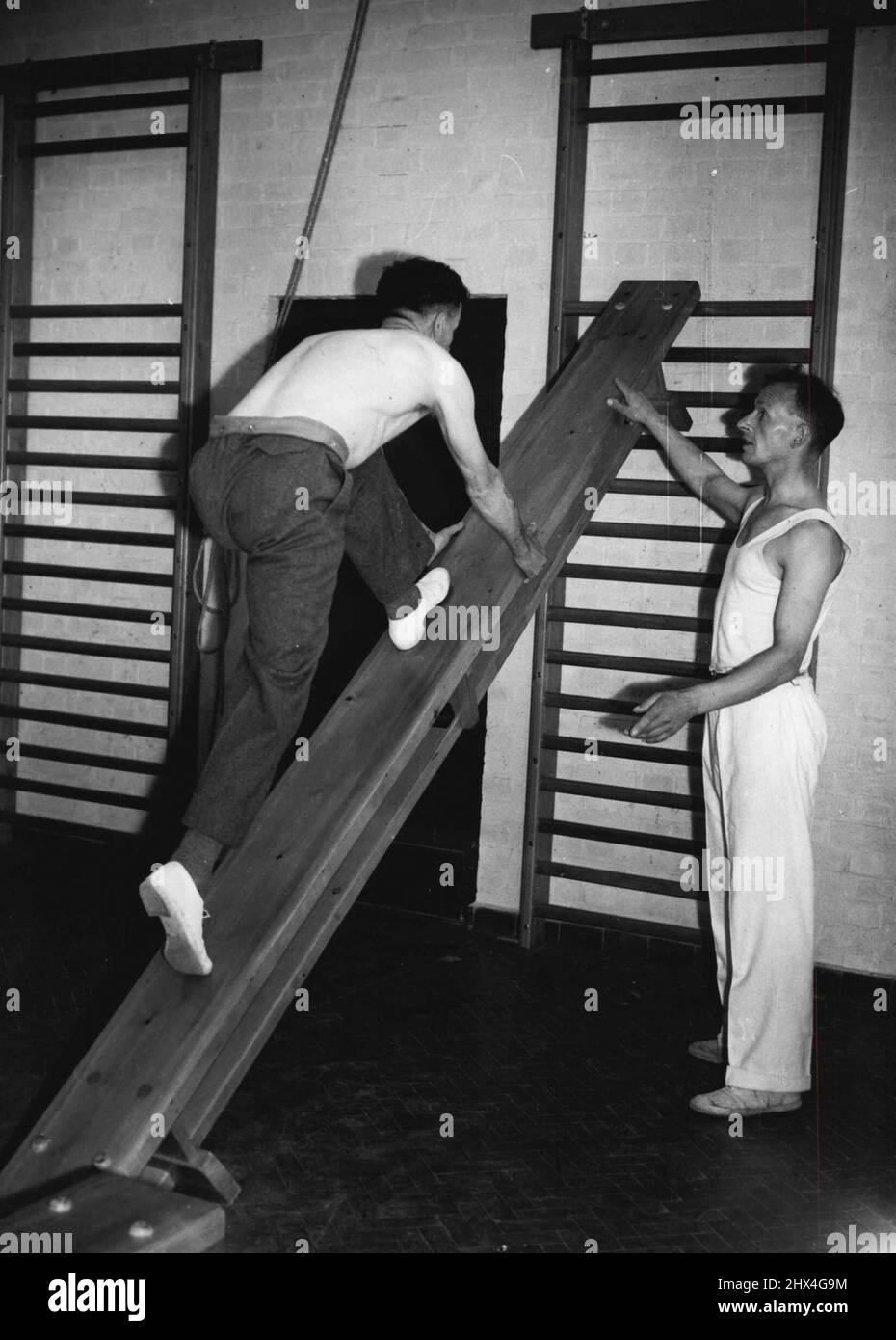 Steel Works Has Its Own Sanatorium -- Instructor Ernest Graves puts Charlie Smith through inclined bench exercises in the gymnasium. Mr. Smith, an assistant operator on coke ovens, fell into an acid bath up to his knees. September 21, 1951. (Photo by Pictorial Press). Stock Photo