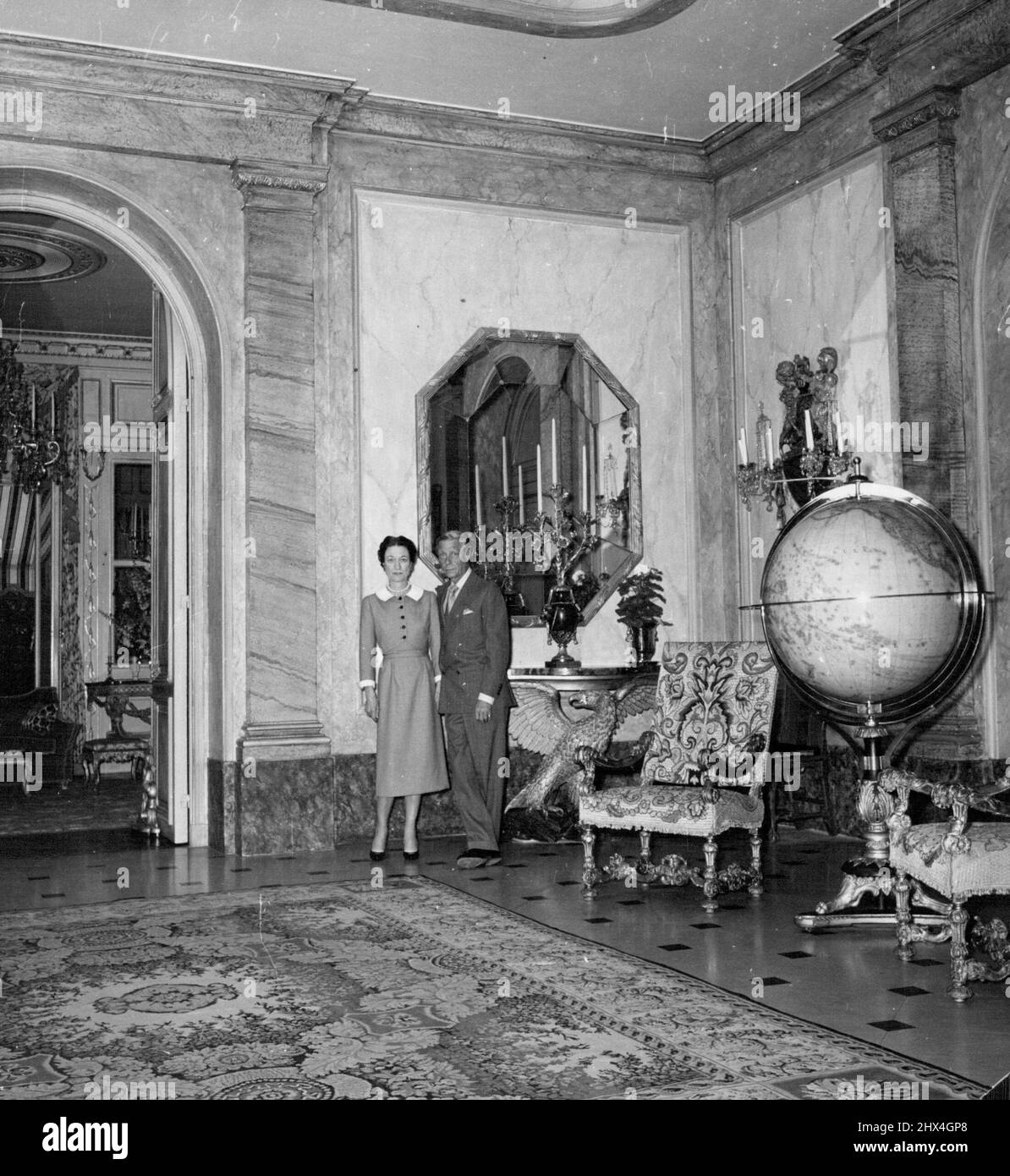 Exotic candelabra hang in an entrance hall panelled with green and pink marble and carpeted with Persian rug. Two richly carved Louis XIV chairs set the Period. July 26, 1955. (Photo by Daily Mirror) Stock Photo