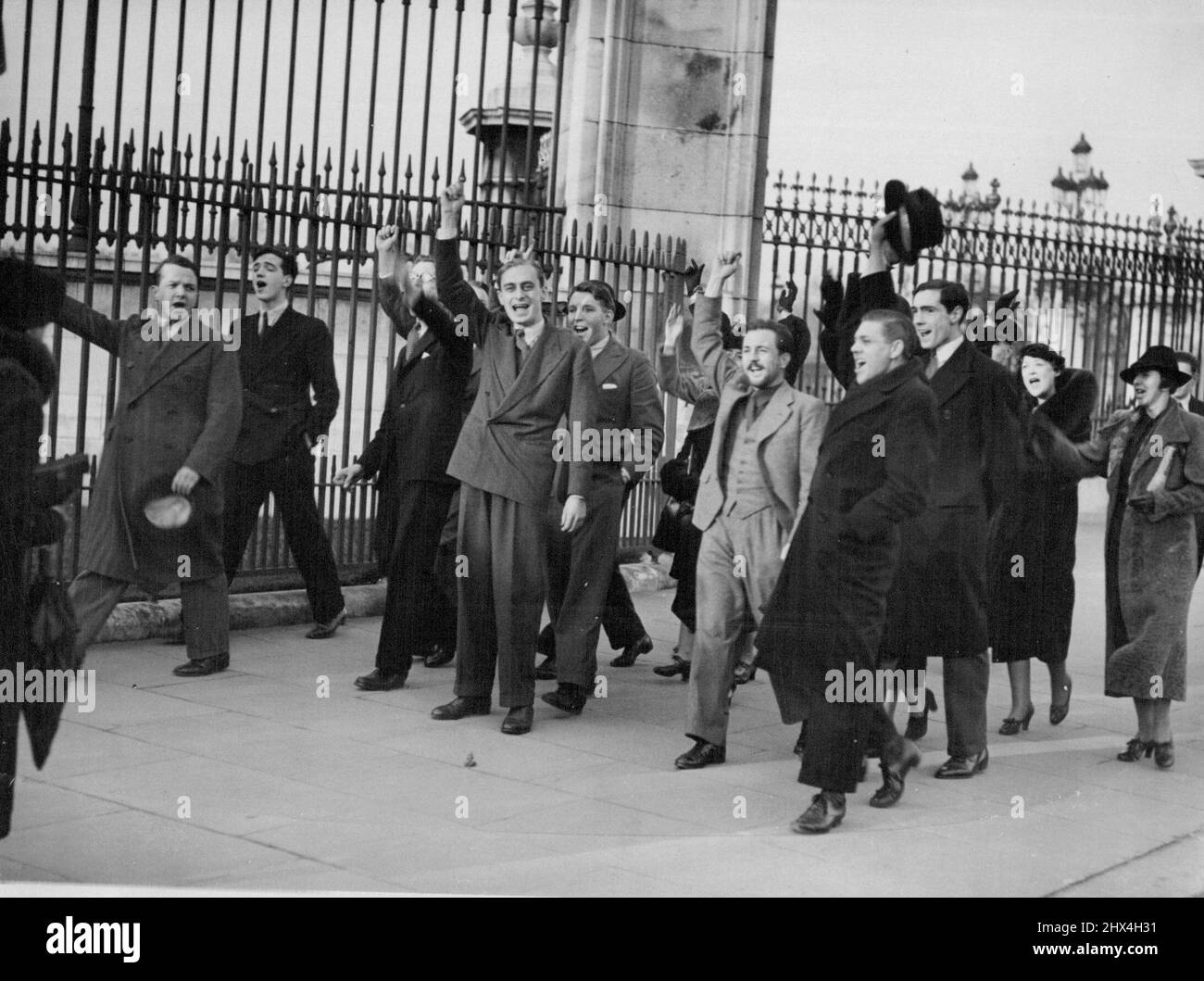 Young Men Give Three Cheers For The King At Buckingham Palace Young Men Giving three Cheers for the King Out Side Buckingham Place. London, Eg, December 4 --- Since It was Announced Yesterday that king with Mrs. Reported to be in Favour of Marriage with Mrs. Ernest Simpson, an American crowd has been continuously at the gates of Buckingham palace waiting for a glimpse of his majesty. At midday today party of his majesty. At midday today party of young men and girl gave three cheers for the King. January 25, 1937. (Photo by Associated Press Photo). Stock Photo
