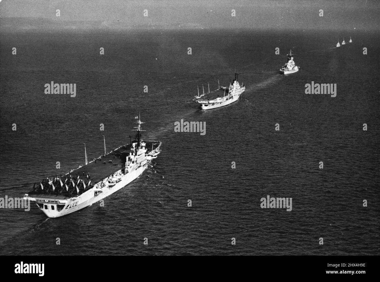 British Home Fleet to Show The Flag - An aerial view as the Home Fleet heads down the English Channel. Nearest camera is the light aircraft carrier 'Theseus', with aircraft on her flight deck. Ahead of her is the carrier 'Illustrious' and the 35,000 ton battleship 'Duke of York'. Leading the line are the attendant cruisers. Britain's Home Fleet has left Portland Harbour on a 12 weeks' autumn cruise to the West Indies. The first three days of the journey will be occupied with a mock battle in which all units will take part. September 23, 1948. (Photo by Sport & General Press Agency, Limited). Stock Photo