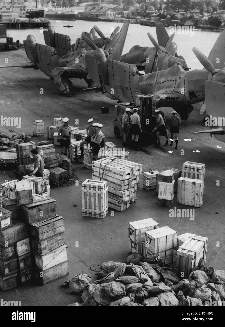 Crew of the new carrier HMAS 'Vengeance' unloading preparing to unload Seamen and stones from the flight deck of the carrier which is along garden Island. March 12, 1953. (Photo by Winton Irving/Fairfax Media). Stock Photo