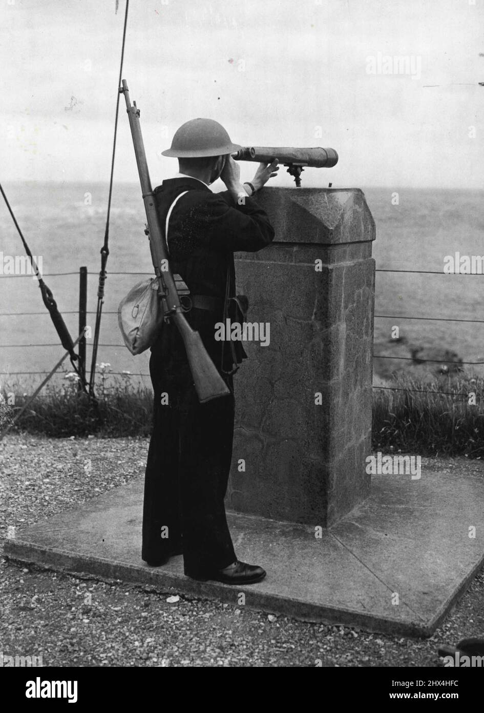 The Watch On The Coast H.M. Coast Guard At War An armed Coast guard on watch at a The day and night watch on the shores of Britain has intensified