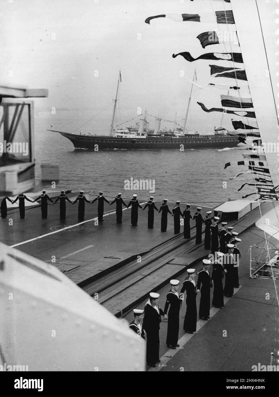 The King Reviews His Fleet At Spithead - The Royal yacht 'Victoria and Albert', passing the aircraft-carrier 'Glorious' as the crew dressed ship. Aboard the Royal yacht 'Victoria and Albert, the King passed through the five-mile lines of 160 warships and merchant vessels when he made his Coronation Review of the British Navy and Mercantile Marine at Spithead. Nearly 300 ships, including 17 from foreign fleets, were reviewed. May 20, 1937. Stock Photo