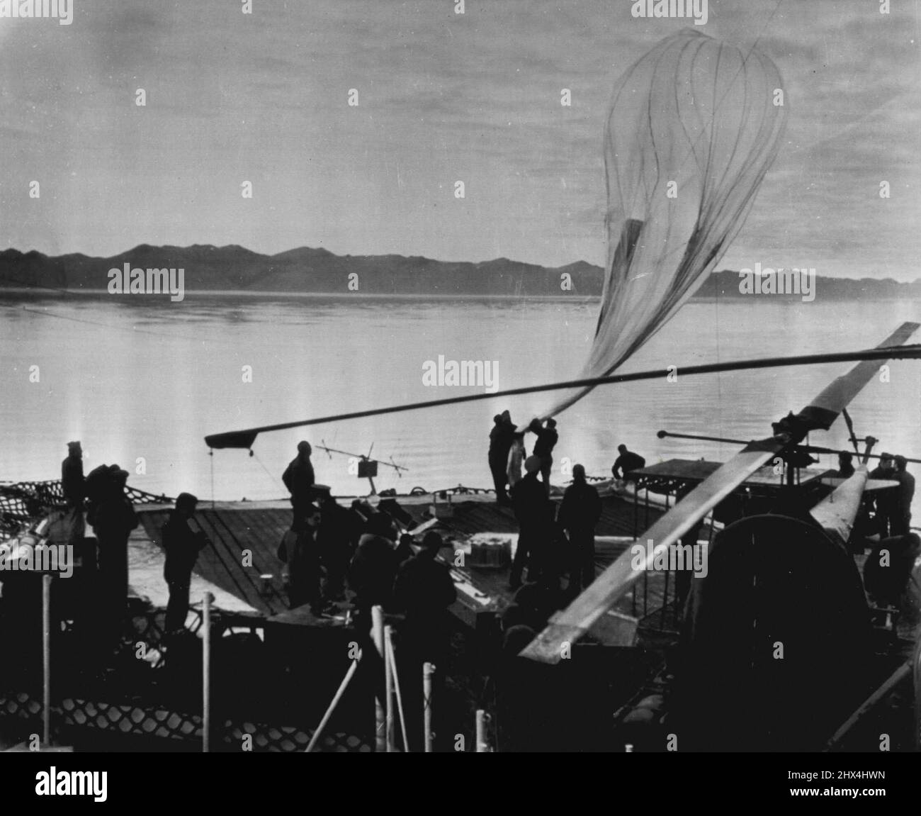 Seek Cosmic Ray Data In Far North -- Crewmen of the Coast Guard Cutter Eastwind launch a plastic balloon from the ship's flight deck during a series of high altitude cosmic ray studies. The tests were conducted by Naval and civilian scientists in August and September off the Greenland coast in the vicinity of the magnetic pole. October 15, 1952. (Photo by AP Wirephoto). Stock Photo