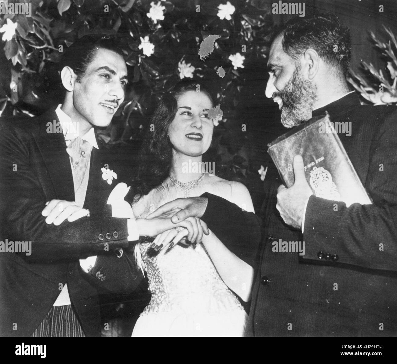 Imam Congratulates Couple - Bashir Ahmed Minto (right), Imam (right) congratulates Princess Fathia,19 of Egypt an her commoner husband, Riad Ghali, 31, after uniting hem in marriage here tonight in a Moslem wedding. The marriage was opposed by King Farouk of Egypt, brother of the Princess. May 25, 1950. (Photo by AP Wirephoto). Stock Photo