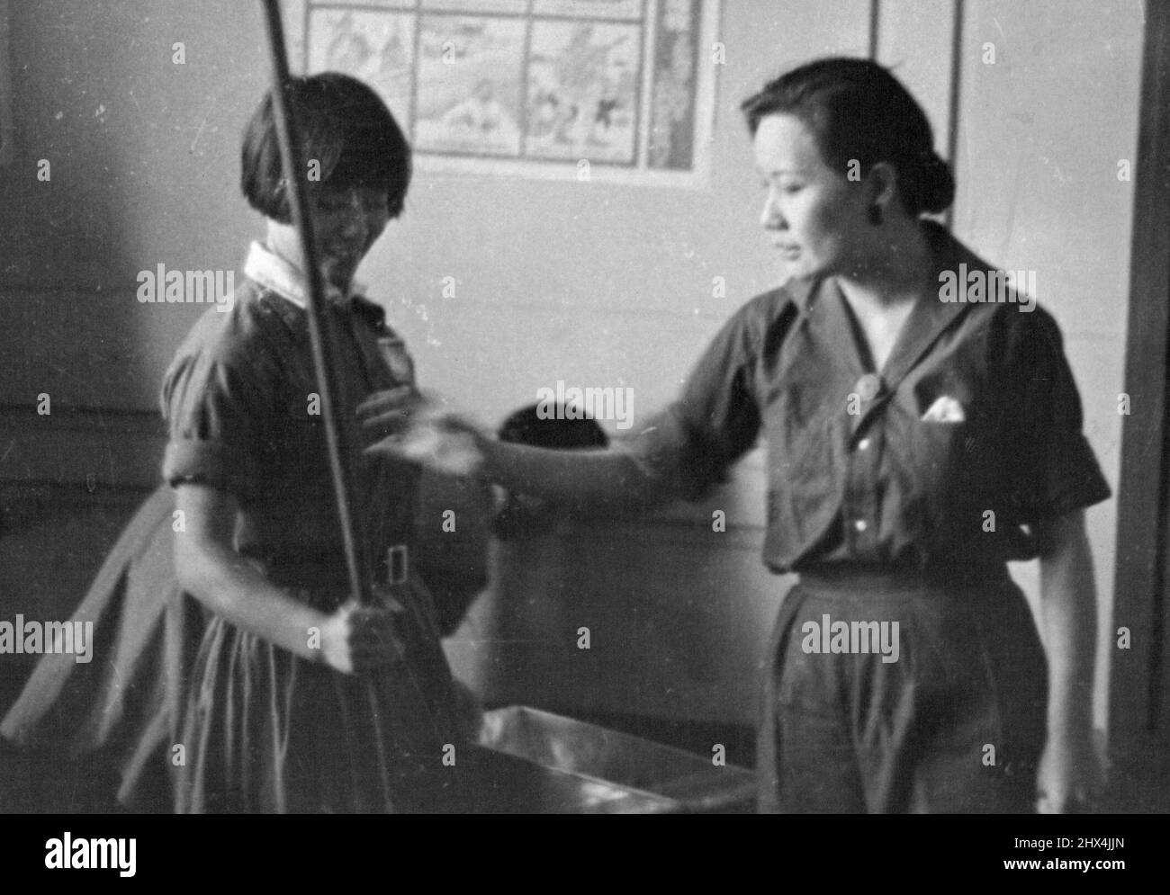 China's First Lady - Also Knows Something About Work -- Madame Chiang Kai-Shek giving instruction in the cleaning of floors. Madame Chiang Kai-Shek, wife of China's Generalissimo, thinks nothing of rolling up her sleeves and instructing members of the women's war service corps in their work. November 21, 1938. (Photo by Associated Press Photo) Stock Photo