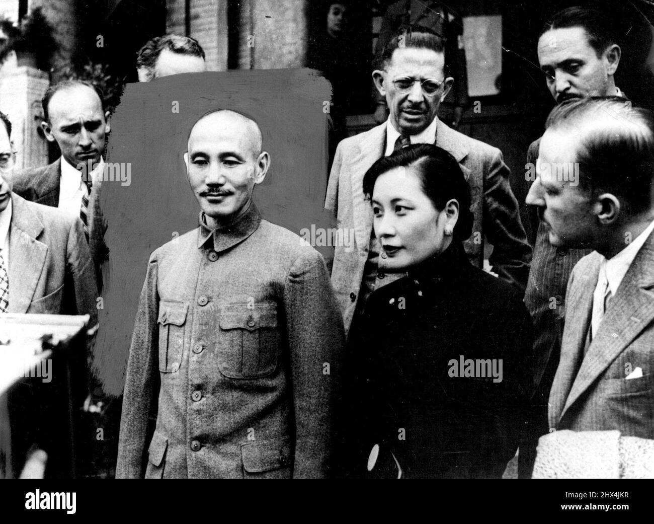 Chain's 'Strong Man' Receives The Press Wife Acts As Interpreter -- General And MME. Chiang Kai-Shek photographed with Journalists after the interview in Nanking. MME. Kai-Shek is here seen to be a pretty woman, on her high collar she *****. MME. Chiang Kai-Shek, who holds as much power in China as her famous husband, General Chiang Kai-Shek, acts as interpreter when the press are interviewed. All these interviews are held in secret plades, as are other meetings of importance, ***** of their important position for ***** . November 10, 1937. (Photo by Keystone) Stock Photo