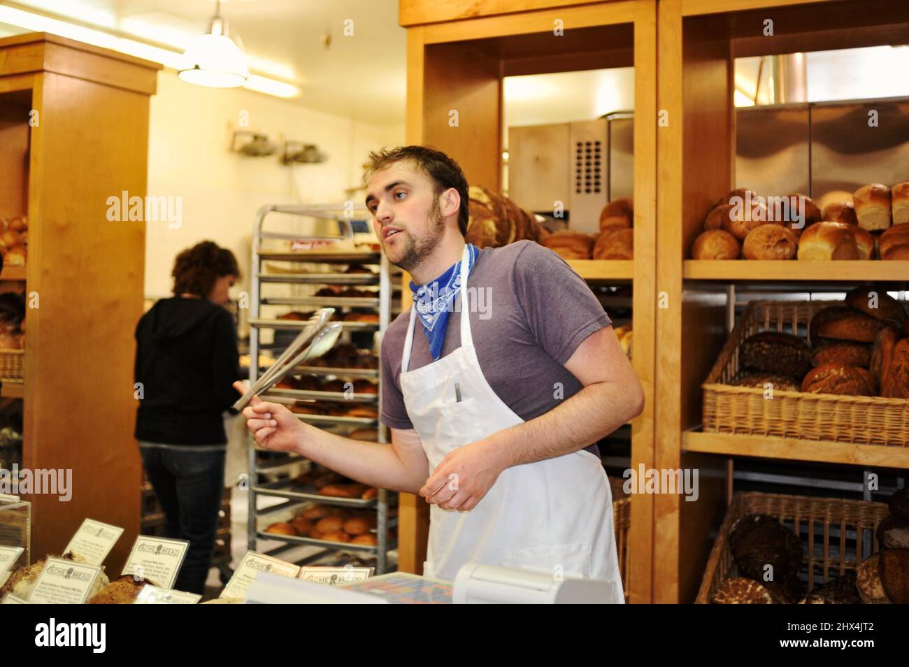 Employee taking orders at the Acme Bread Company bakery counter at