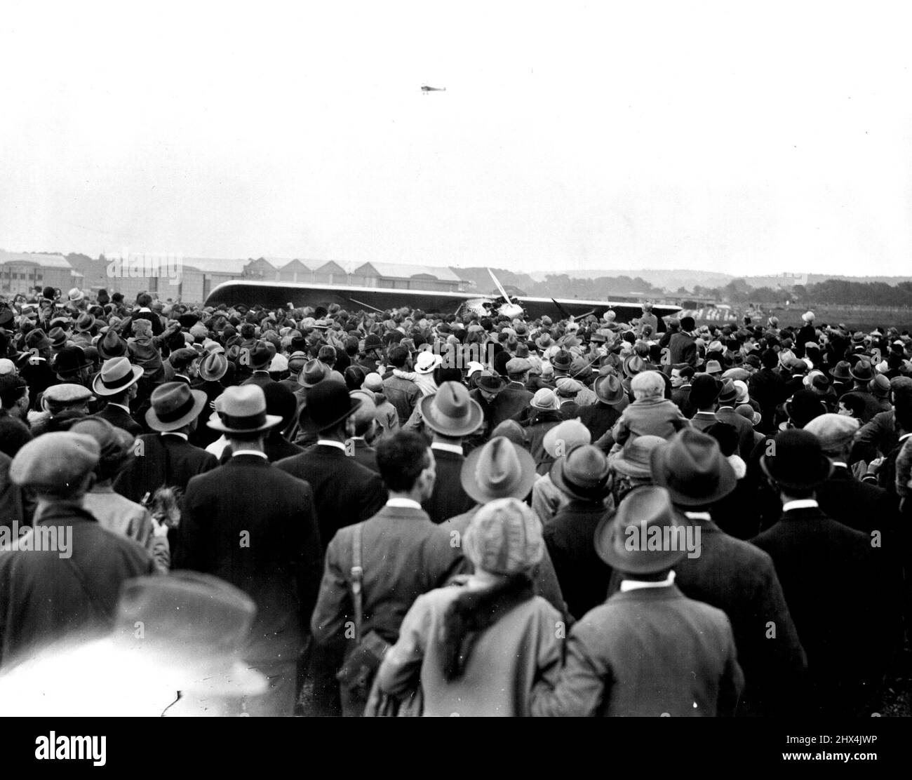 London's Magnificent welcome to capt. Charles Lindbergh, the hero of the Trans-Atlantic Flight. An Enormous crowd of over 100,000 Assembled at Croydon Aerodrome on Sunday, May 29th, to welcome Capt. Lindbergh as he arrived from Brussels. Aeroplanes Escorted him from the English coast to the Aerodrome. A general view of the crowd surging round the plane immediately it landed. July 06, 1927. Stock Photo