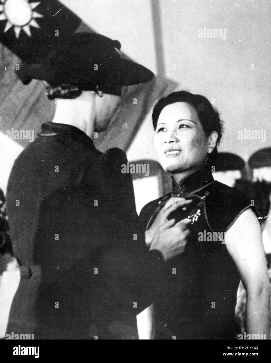 Madame Chiang Kai-Shek Honored -- Miss Lily K. Haass (left), A Y. W. C. A. Secretary, pins an emblem of honor on the gown of China's first Lady, Madame Chiang Kai-Shek, at a Ceremony in Chungking. July 4, 1941. (Photo by Associated Press Photo). Stock Photo
