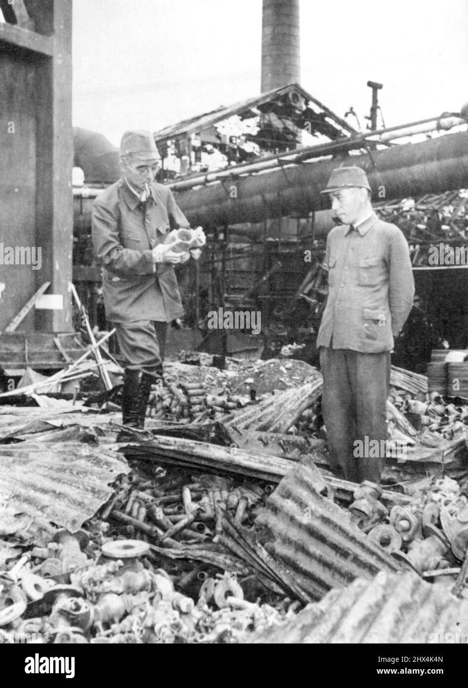 Jap Tycoon Examines Wrecked Factory -- Ryozo Asano, (left), spokesman for the Zaibatsu, the small group of men who own and direct virtually all of Japan's industry, wears a uniform as he examines the wreckage of his Tokyo steel plant which was blasted by Doolittle's raiders, April 18, 1942. Man in uniform on the right is unidentified. October 23, 1945. (Photo by Associated Press Photo). Stock Photo