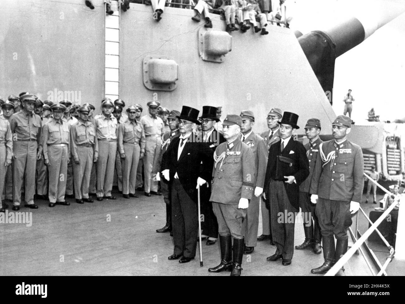 Japanese Officials Arrive U.S. Battleship For Surrender Ceremony -- The Japanese military and diplomatic delegation, headed by Foreign Minister Mamoru Shigemitsu (with cane) and General Yoshijiro Umezu (front, right), Chief of the Imperial General Staff, arrive aboard the U.S. 'battleship Missouri to attend formal surrender ceremonies, as Allied military officers look on. The Japanese capitulation documents were signed on Sept. 1, 1945, aboard the 45,000-ton battleship in Tokyo-Bay, south of the Japanese capital. June 9, 1945. Stock Photo