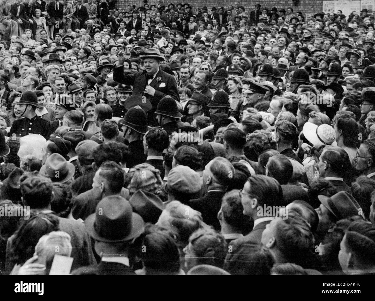 Churchill Hailed On Election Tour -- The Prime Minister stands in the leading car of a long procession passing through densely-crowded/Trinity-street, in blitzed Coventry, where he received a great ovation from the people. Making a ten-speeches-a-day election tour, Mr. Churchill, Conservative leader, ended the first day in the Midlands tired but triumphant, his campaign taking on the appearance of a victory celebration, with men and women of all political parties thronging the route to cheer the leader of the Coalition Government which led Britain to victory in Europe. June 26, 1945. Stock Photo