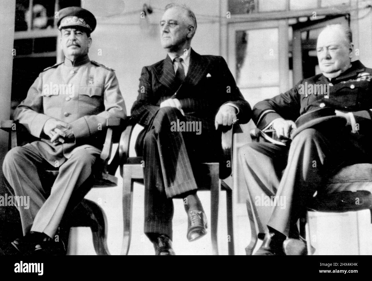 Principals At Teheran Conference -- Joseph Stalin, Russian premier (left), sits with President Franklin D. Roosevelt of the United States and Prime Minister Winston Churchill (right), on the porch of the Russian Embassy at Teheran, Iran, during their four-day conference at which they drew plans to concentrate the total military might of Russia, United States and Britain on a 'Relentlessly Increasing' Basis Guaranteeing victory over Germany. This is one of a series of photos on the conference made by U.S. Army 12th Air Forces photographers and pleased by the War Department in Washington. Decemb Stock Photo