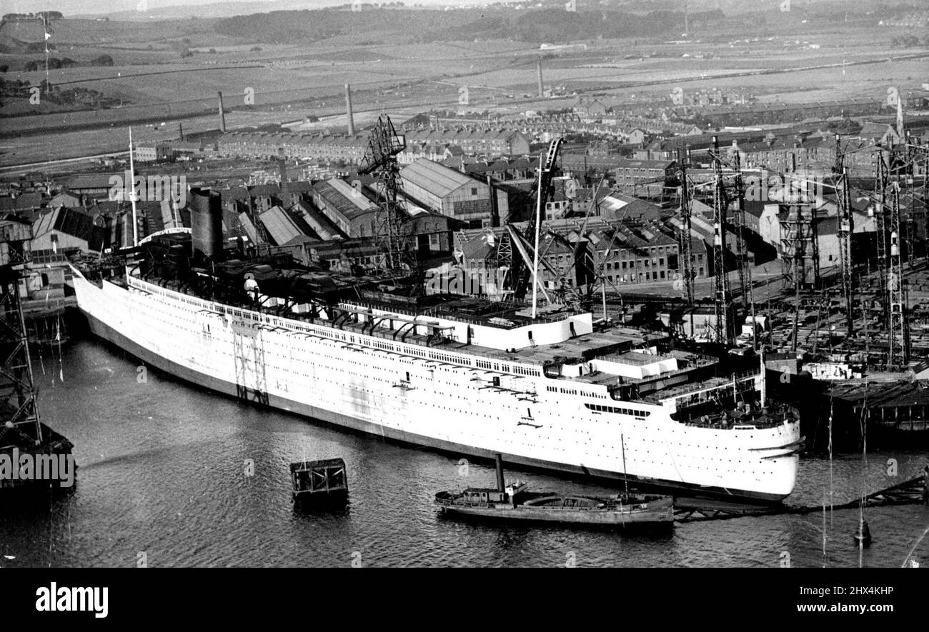 'Queen Mary' Taking Shape -- An aerial, view of the mammoth 'Queen Mary' at Clydebank yesterday, July 31. This view allows the boom which has been erected round Her stern, to protect the screws of the liner.A funnel has just been erected on the giant liner 'Queen Mary' which is now being fitted out at Clydebank. When completed the 'Queen Mary' will be one of the largest liners afloat, and will be a worthy British representative on the seas, as it is built on equally sumptuous lines to that of the French marvel 'Normandie'. The question now arises, will she beat the Normandie's time for an Atla Stock Photo