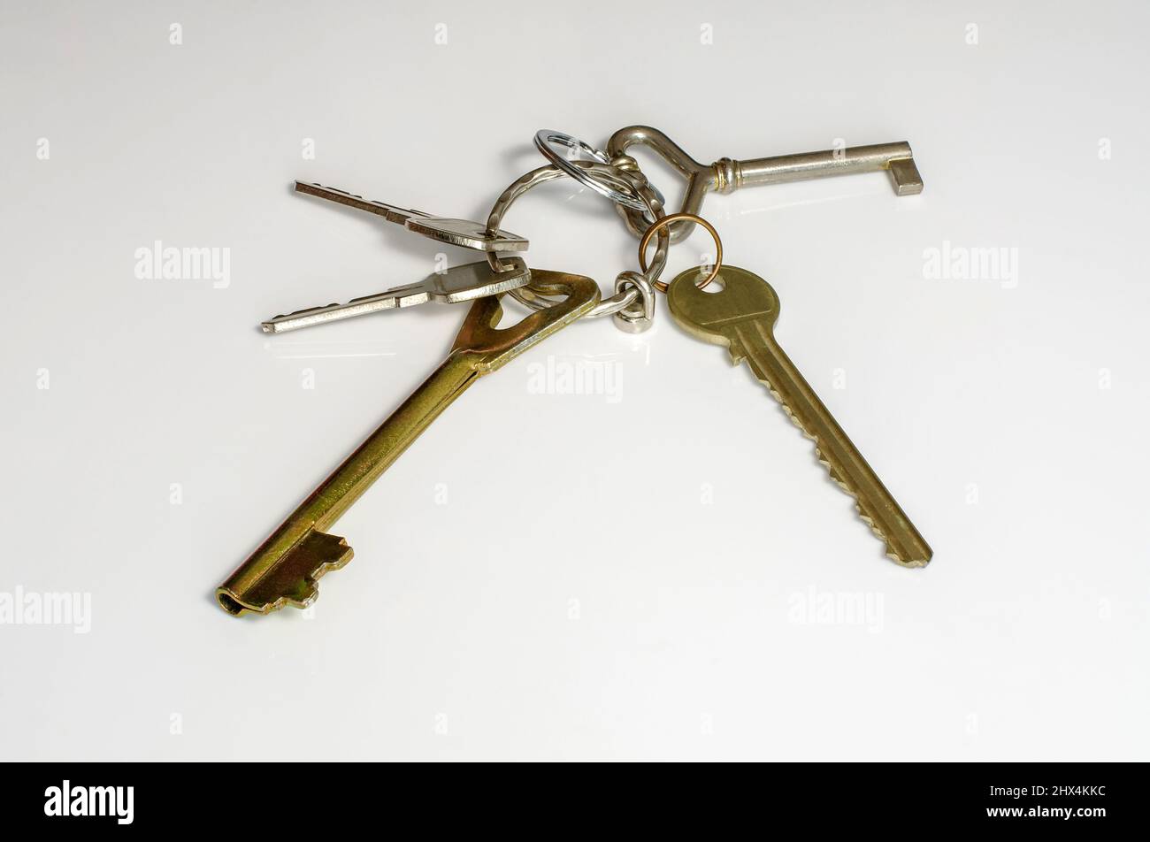 Keys to an apartment, house on metal wheels, on a white background, different types, five keys Stock Photo