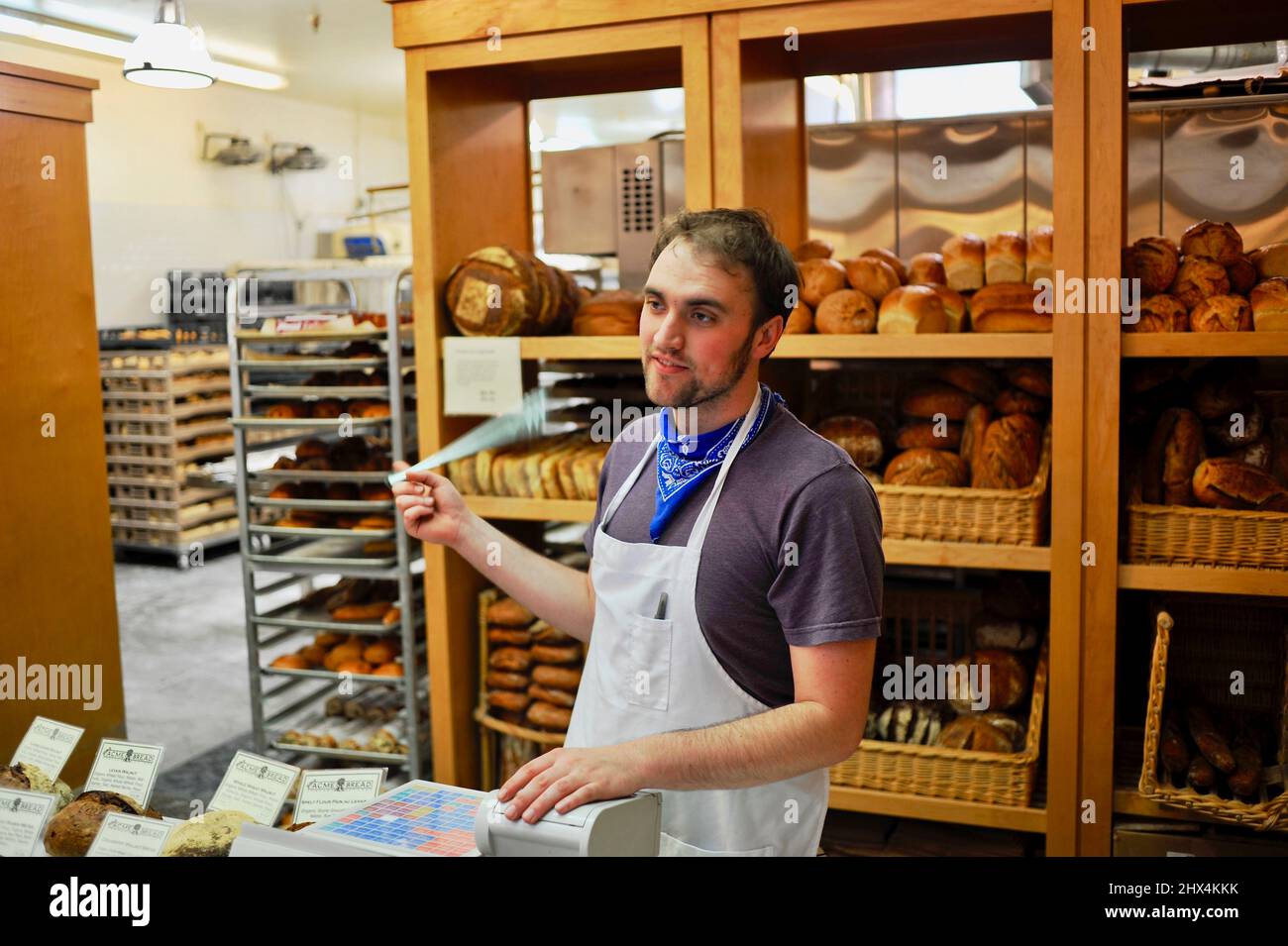 Employee taking orders at the Acme Bread Company bakery counter at