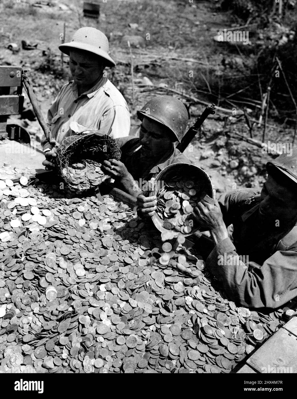 Big Fall In Money Cash Crashed! American soldiers reloading a truck with half a million dollars worth of Filipino and Americans coins which had been blown from it by direct artillery fire on Luzon. March 19, 1945. (Photo by USA Army Signal Corps Photo). Stock Photo