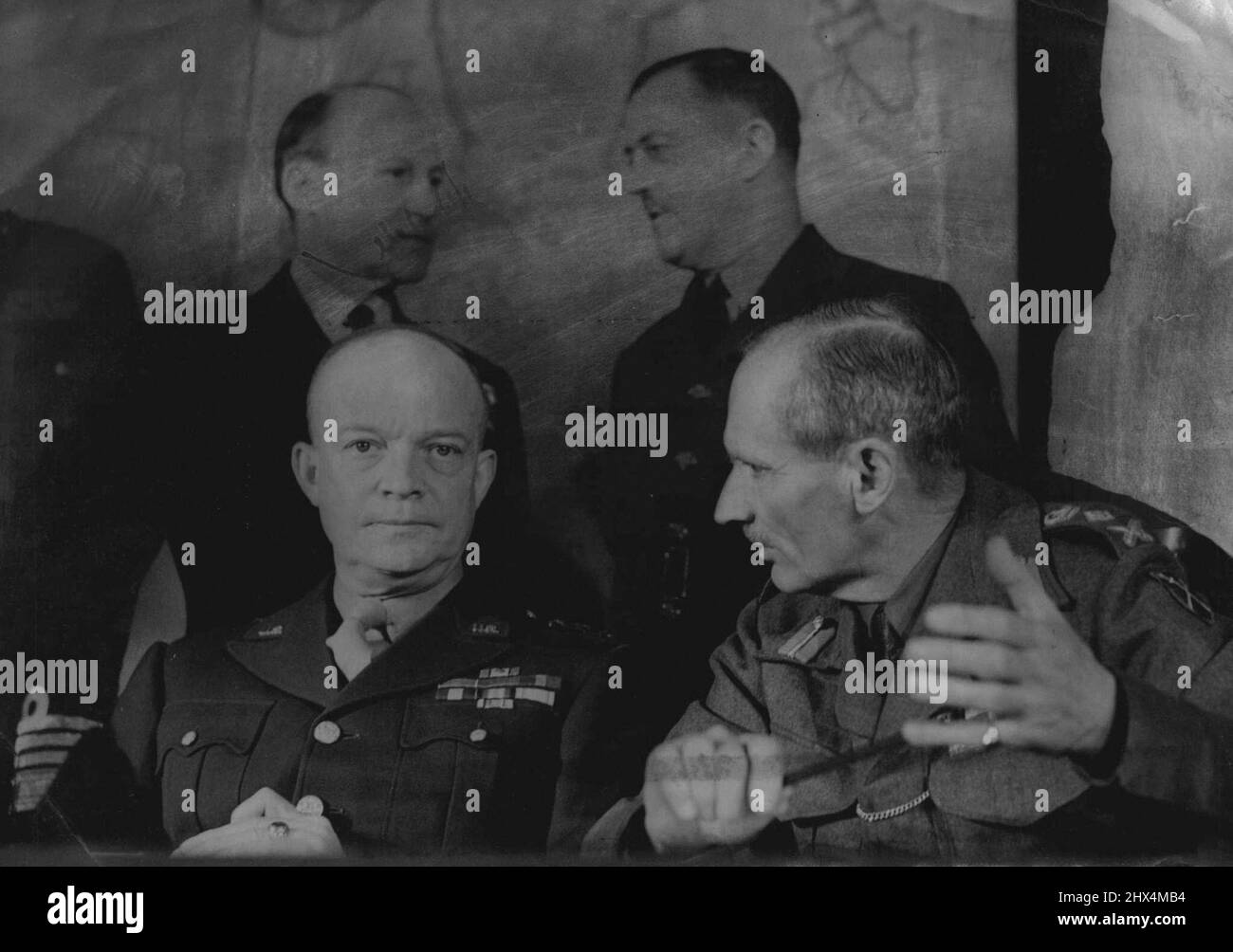 Allied Supreme Command In Conference - First Pictures -- General Dwight D. Eisenhower, Supreme Commander, listens while General Sir Bernard Montgomery, C-in-C., British Group of Armies, makes a point at the conference. Behind are Admiral Sir Bertram Ramsay, Allied Naval Commander (left) and Air Chief Marshall Sir Trafford Leigh Mallory, Air C.-in-C. For the first time the Allied Supreme Command were photographed in conference at their headquarters. February 1, 1944. Stock Photo