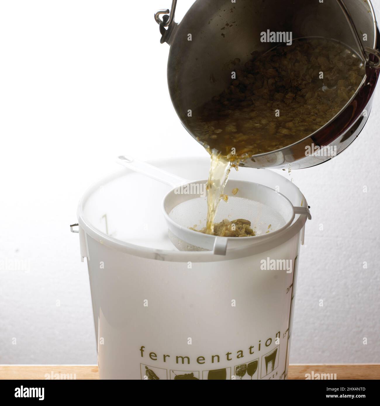 Straining beer hop liquid through a sieve to make Homebrewed Beer