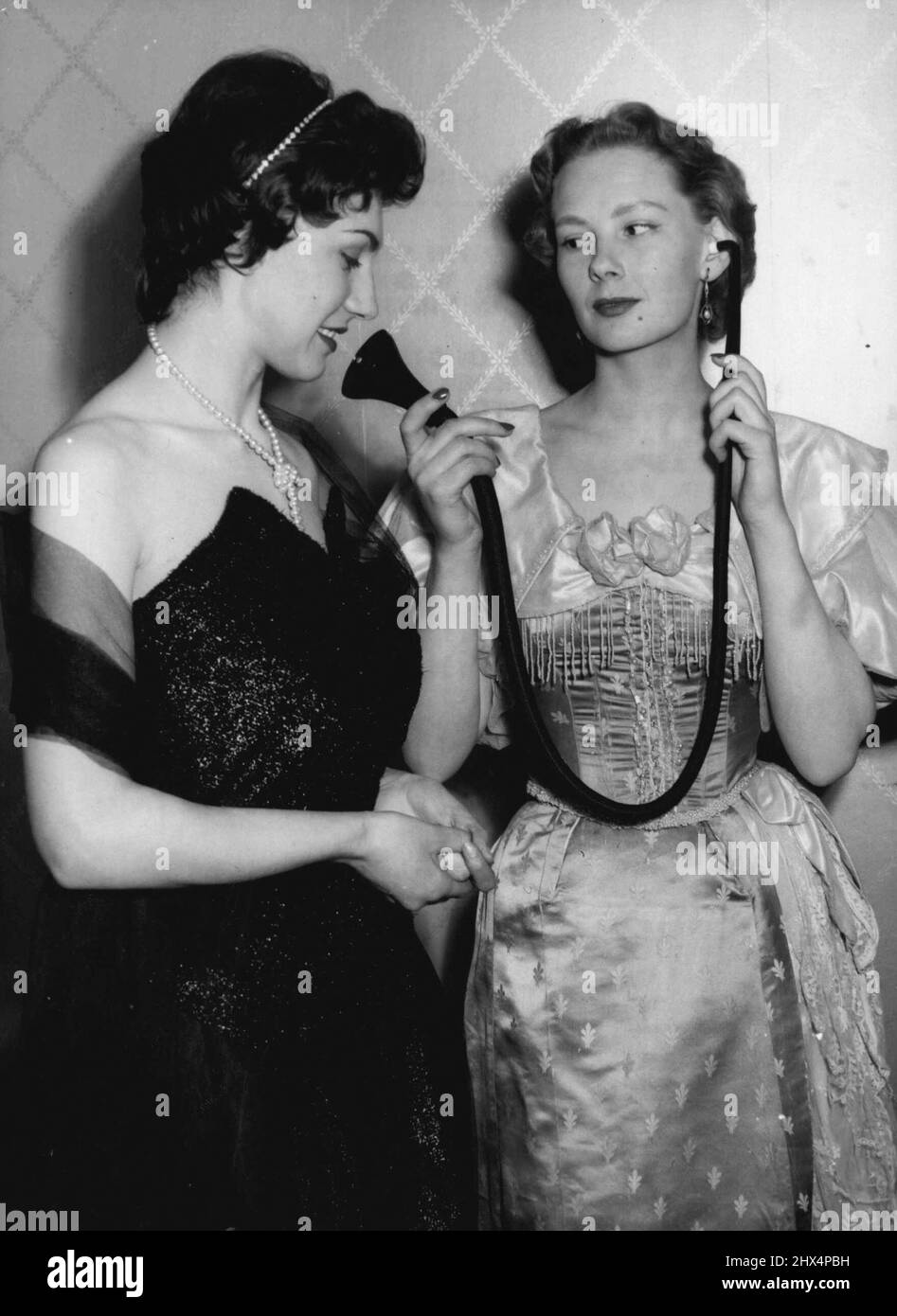 Fashionable Hearing - The old You Know - the New You Cannot See. Hazel Innes, on the right shows an Edwardian type of hearing aid to Gillian Davis, who is in fact wearing a modern hearing aid which is incorporated in the Pearl Necklace she is wearing, the main "Michrophone" part being in the Cluster of Pearls in the front of the Necklace.A Unique Fashion show was held in London today, ***** the latest trends in ***** Hearing Aids.Among those ***** were models ***** ties, Scarved and ***** for men and in ear-rings, ***** scarf clasps, Hair-bands and Necklaces for women. May 10, 1955. (Photo by Stock Photo