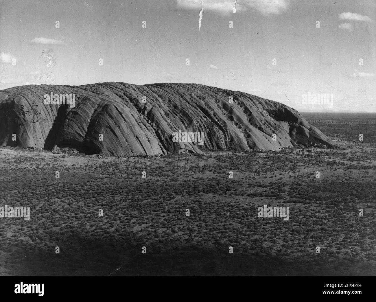 Its impact is impression ***** Ayers Rock from the air. The future of one of Australia's greatest tourist attractions - the mighty monolith of Ayers Rock - is now secure following the discovery of big reserves of underground water in the area. November 25, 1955. (Photo by The Telegraph Newspapers Co. Ltd.). Stock Photo