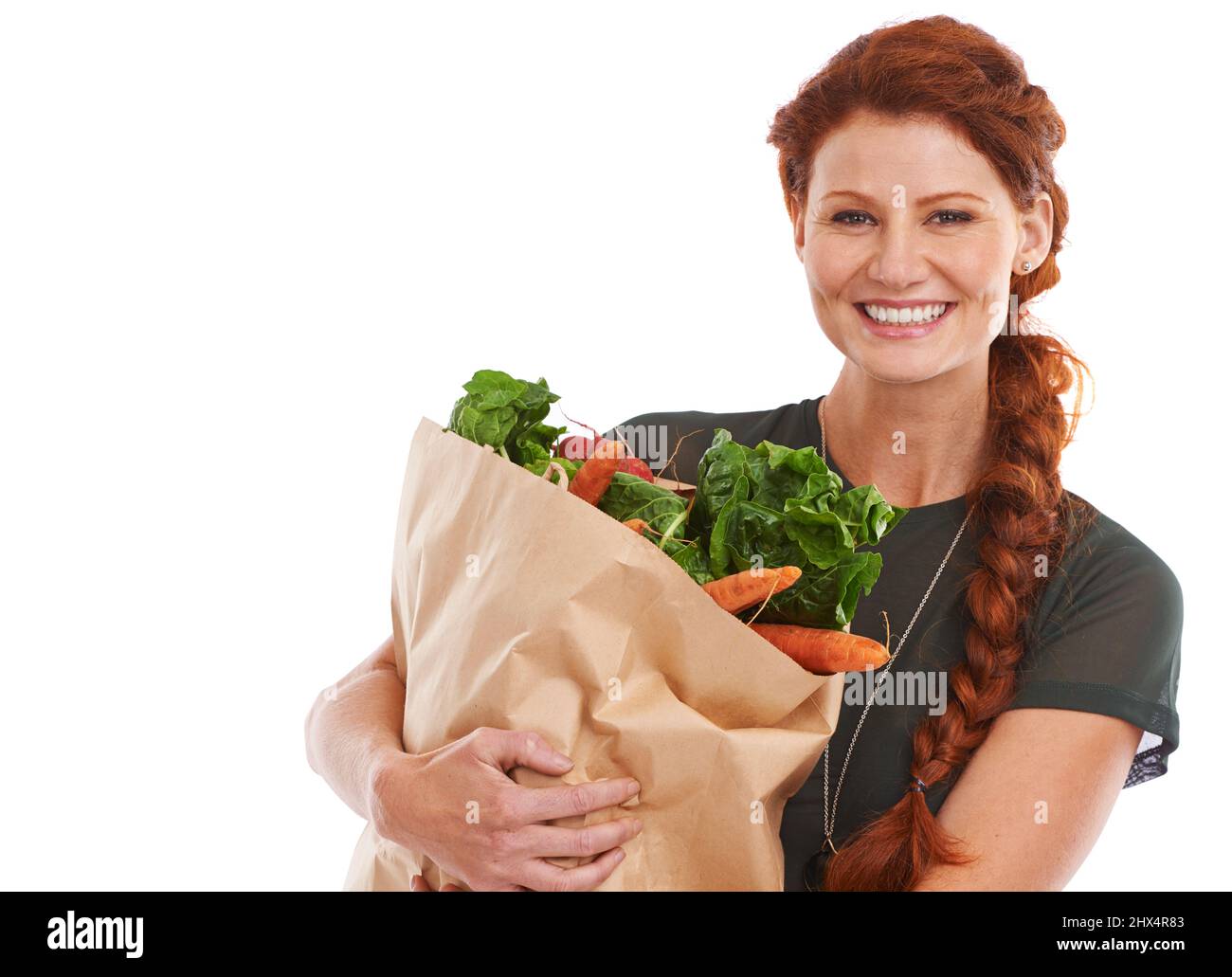 She makes healthy eating a priority. Studio shot of a beautiful young woman holding a shopping bag full of fresh vegetables. Stock Photo