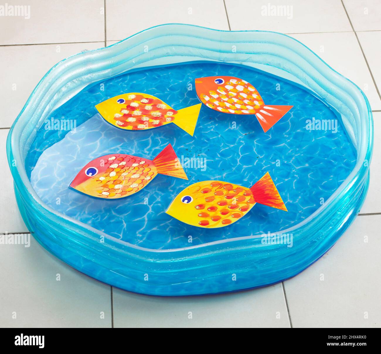 Blue paddling pool with homemade fish floating on water Stock Photo Alamy