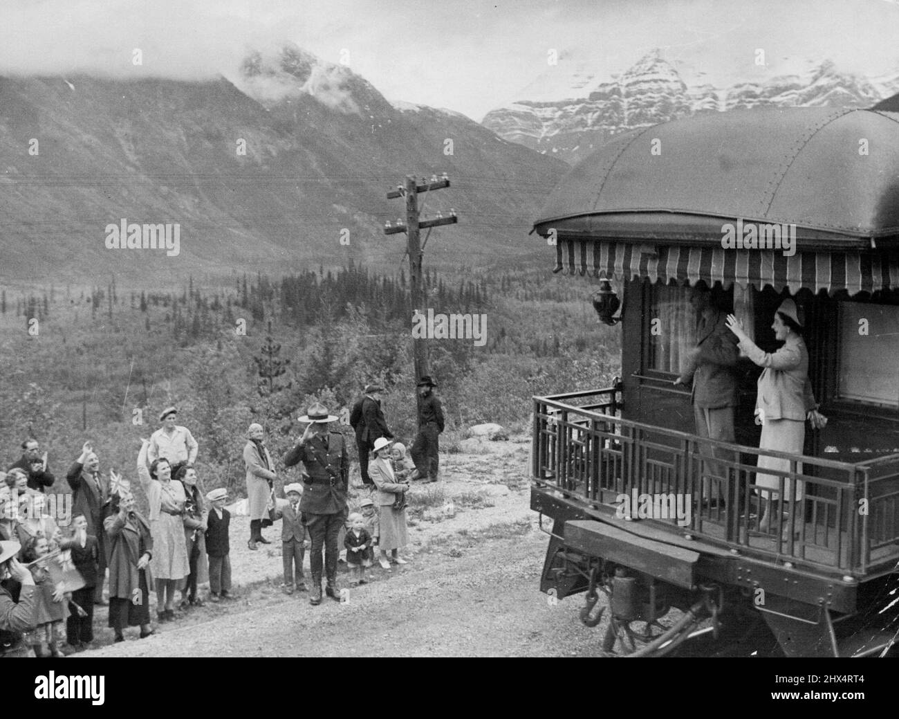 Royal Canadian Tour: The King and Queen in the Rockies -- Our photograph show the King and Queen on the rear platform of their coach, which the Rockies and the lower slopes of Mount Robson in the background. July 03, 1939. Stock Photo