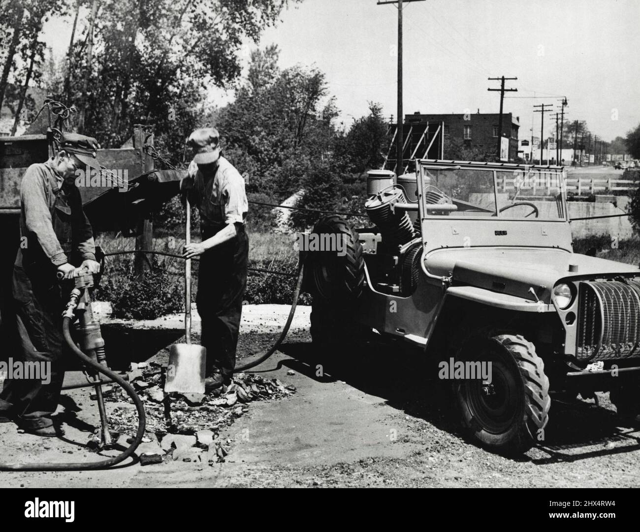 Jeep-of-All-Trades -- Highway Repair... The jeep can operate pneumatic tools, as shown here, which makes it a good bet for small townships in rural communities for quick, efficient road repair and similar jobs. September 16, 1945. (Photo by C.J. Nichols, International News Photos). Stock Photo