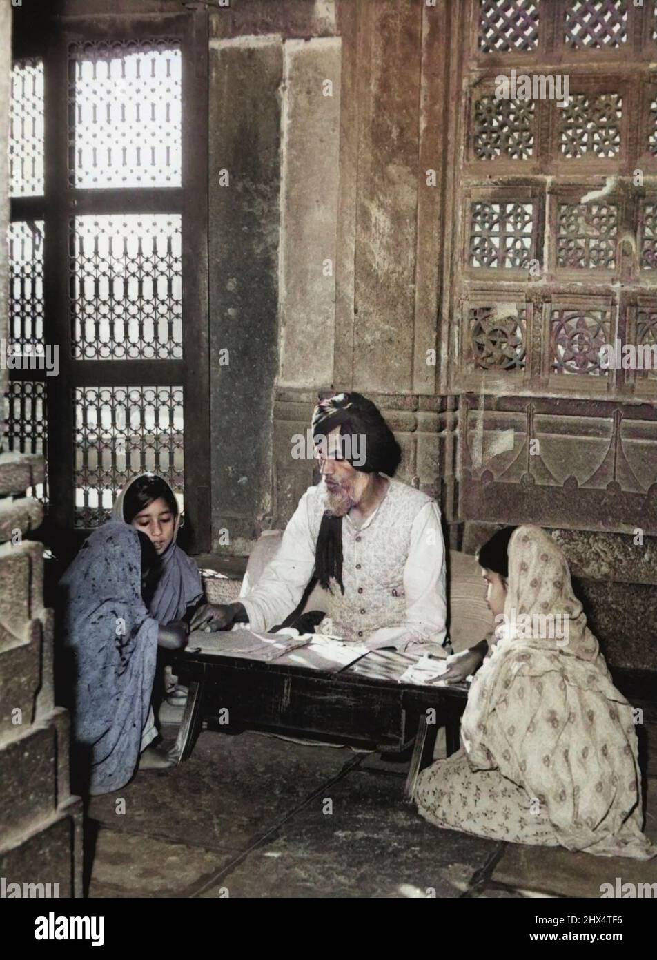 Shrine Of Learning - In the Quiet of an Old Muslim Shrine, a teacher gives lessons on the Koran to young Muslim girls. This picture was taken at Ahmedabad, Capital of Gujarat. It is one of the shrines of the old Modul Emperors, now used primarily as religious schools. Both teacher and pupil have to sit on the ground with their books on special racks. September 01, 1953. (Photo by Paul Popper, Paul Popper Ltd.). Stock Photo