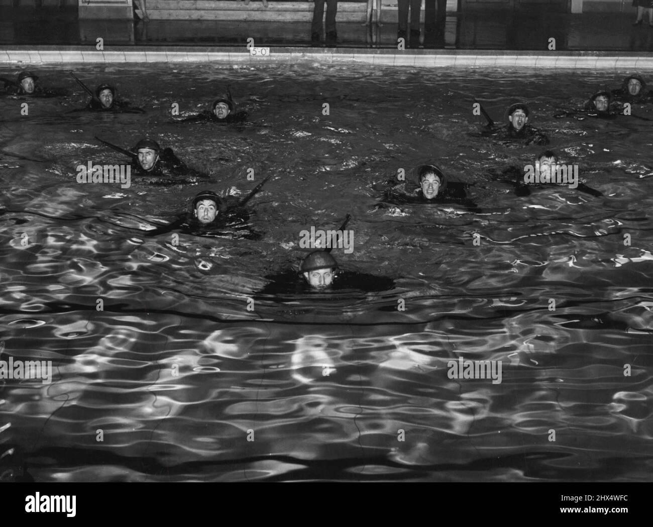 Toughening Up Army Clerks -- Members of the Royal Army Pay Corps training at a swimming bath in the London Area. Apart from the 'pen and ink' duties of the Royal Army Pay Corps, the men are put through strenuous 'battle' training of the commando type which includes swimming in full kit. September 25, 1942. (Photo by Fox Photos). Stock Photo