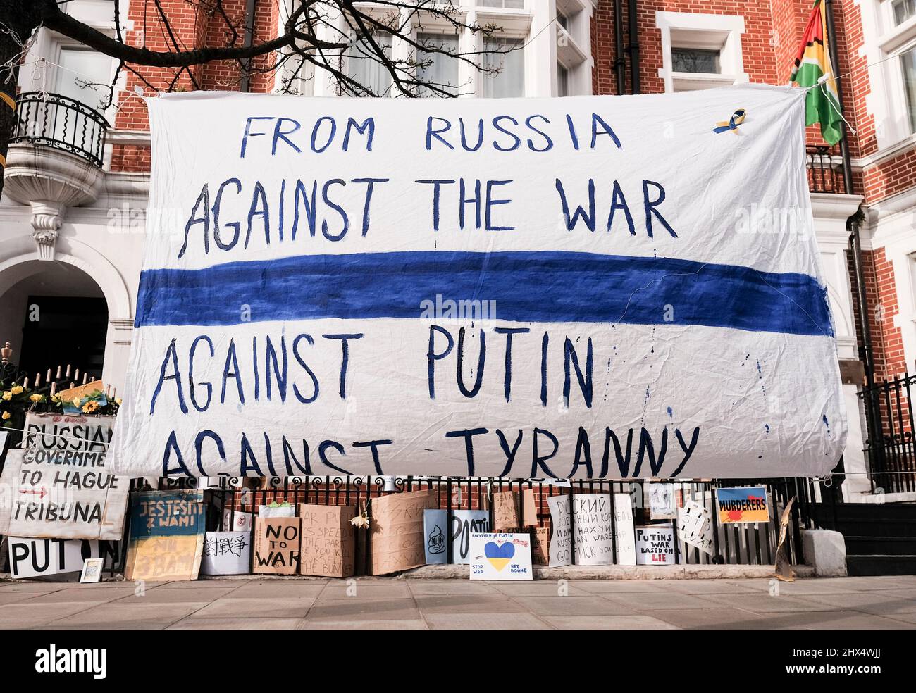 London UK, 9th March 2022. A banner declaring opposition to the war from Russian citizens is displayed opposite the Russian Embassy. The Russians Against War movement has adopted a white and blue flag as a symbol of their protest.The flag replaces the red stripe of the Russian flag to remove the association with blood and violence, along with military power and authoritarianism. It also references the historic flag of Veliky Novgorod, where the government of the Novgorod Republic had a reputation for developing democratic governance. Stock Photo