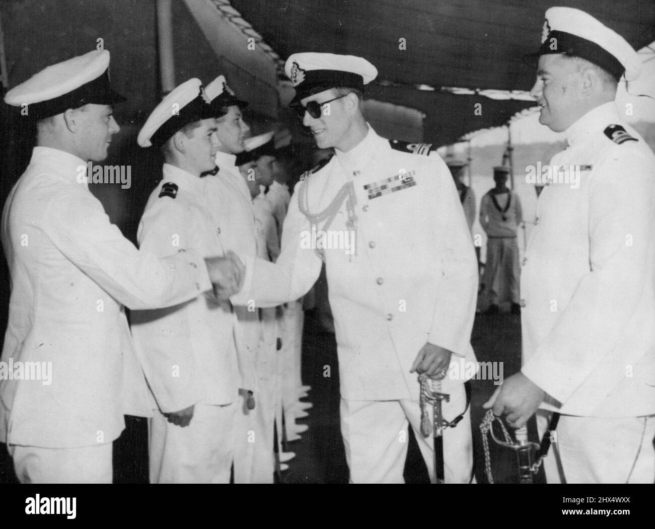 The Duke of Edinburgh Takes Over Lieutenant Commander The Duke of Edinburgh, accompanied by Lieutenant Commander A. L. Harper (right), from whom he is taking over command of HMS Magpie, shakes hands with chief petty officer V. H. Clark, D.S.M., Coxswain, of Purbrook, Hampshire, Sept. 2, at Malta. September 11, 1950. (Photo by Associated Press Photo). Stock Photo