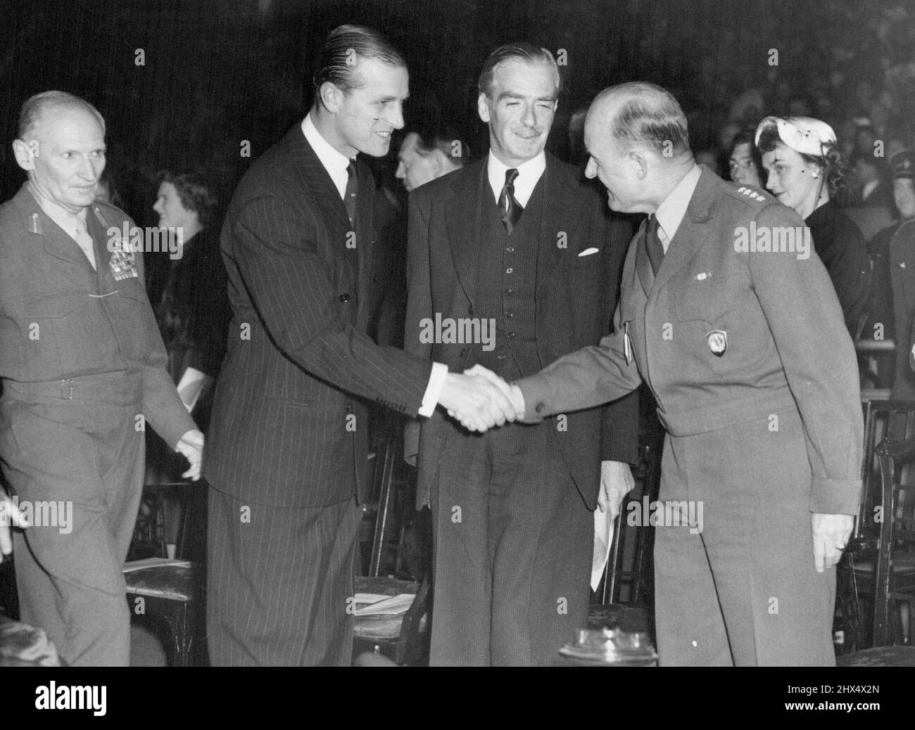 Duke At El Alamein Reunion London: Field Marshal Viscount Montgomery of El Alamein (left) watches as the Duke of Edinburgh shakes hands with General Grienther (right), supreme Allied Commander in Europe, during the 1953 El Alamein reunion, held at the Empress Hall, Earl's Court. Also looking on is Foreign Minister Anthony Eden (second from right), who was the principal speaker. The remain is held annually for men of Montgomery's famed 8th Army the 'Desert Rats.'. October 23, 1953. (Photo by Herbert Ludford, United Press Photo). Stock Photo