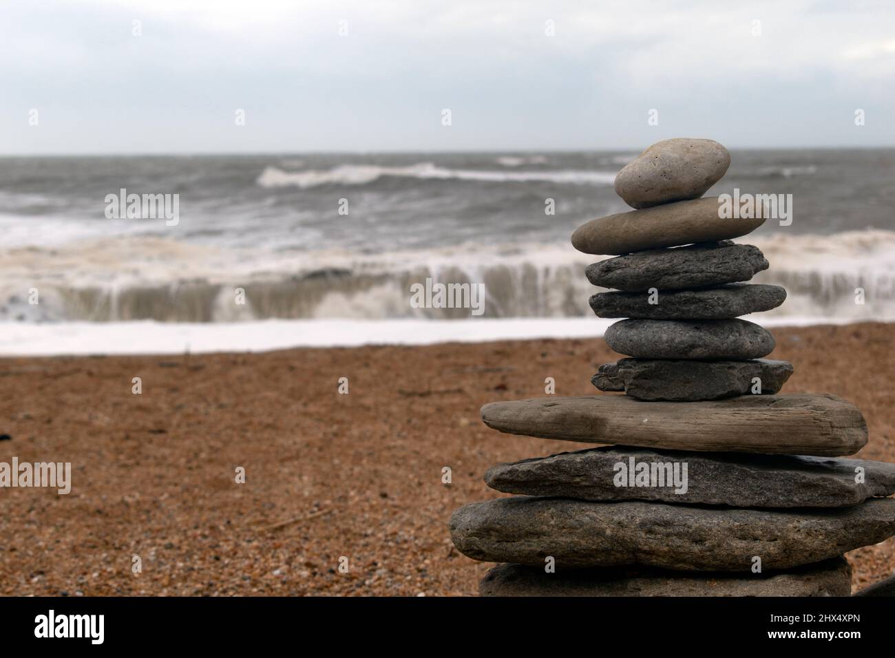 Zen rocks against a backdrop of turbulent seas on an overcast day Stock Photo