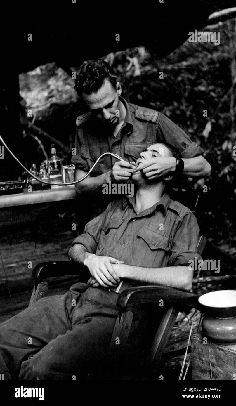 Wau-Mubo area. A dental ***** forward area. Captain J. Garay, of ***** treatment to Pte. G. Verity, of ***** dental post is within range of Japanese *****. August 16, 1943. (Photo by Department of Information, Commonwealth of Australia). Stock Photo