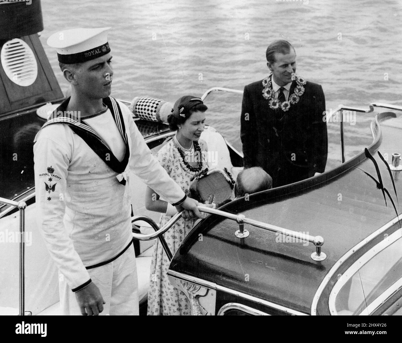 Queen Elizabeth in Tonga - A sad farewell. Queen Elizabeth and the Duke of Edinburgh wore Tongon leis as they stepped into the Royal barge to return to the Gotchic, their visit to the Island Kingdom of Tonga ended. February 03, 1954. Stock Photo