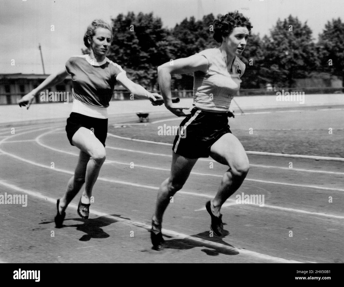 Olympic Girls From 'Down Under' Train At Paddington -- Australian sprinter and hurdler Shirley Strickland hands over to fellow-country woman Verna Johnston as they practice relay changeovers during a training spell with other Australian Olympic Games women athletes at Paddington Recreation Ground. June 19, 1952. Stock Photo