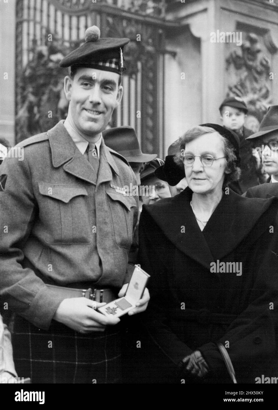 Speakman Receives His V.C. -- Private William Speakman - standing with his mother outside Buckingham Palace - displays his Victoria Cross in its case, after he received it from the Queen at her first investiture of the new reign, in the palace today (Wednesday). He was awarded the ***** for gallantry in Korea. February 27, 1952. (Photo by Reuterphoto). Stock Photo