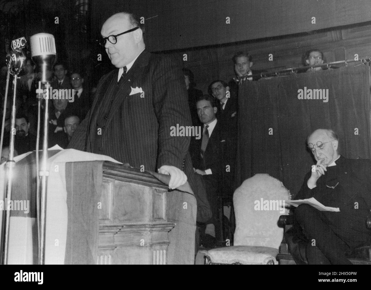 M. Paul-Henri Spaak speaking at the public meeting at the Kingsway Hall.Seated behind him, listening intently with glasses pushed up on his forehead is the Archbishop of Canterbury, Doctor Geoffrey Fisher. European Assembly President Addresses London Meeting, M. Spaak  On Two-Day Visit -- President of the European Assembly, M. Paul-Henri Spaak, who is on a two-day visit to London ***** the invitation of the European movement, addressed ***** large public meeting at the Kingsway Hall, held ***** the auspices of the United Kingdom Council of the European movement.Other speakers at the meeting in Stock Photo