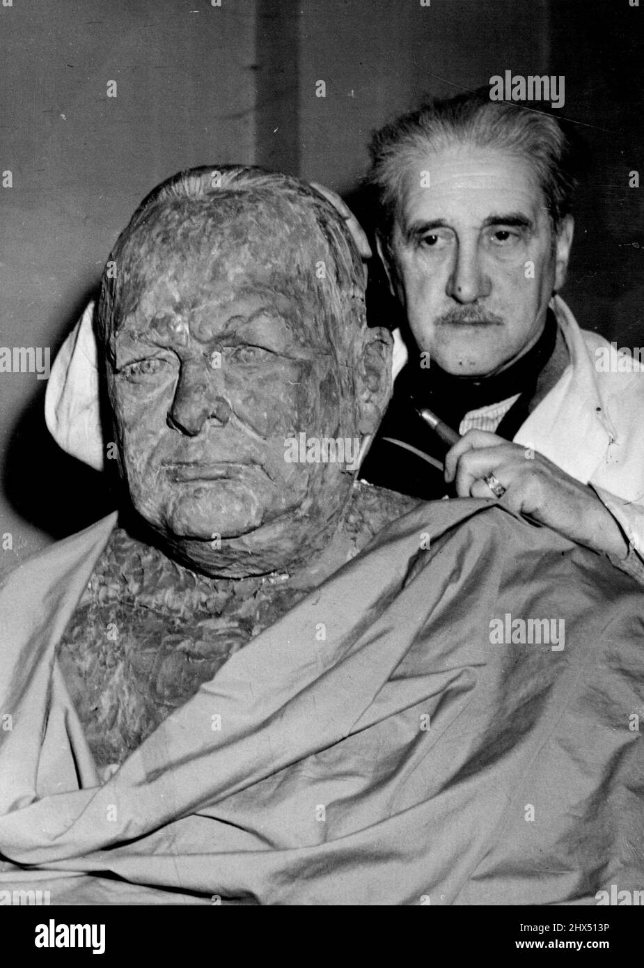 A German Portrays Churchill -- Benno Elkan is seen in his studio at 26 Exeter road, London, NW 2 putting the finishing touches to his bust of Winston Churchill. A German refugee, Benno Elkan, who was born on Dortmund, Westphalia in 1877 and has studied and in Munich, Rome and Karlsruhe, is now sculpturing a bust of Britain's former permier, Winston Churchill, Benno Elkan began work on the bust soon after the battle of Dunkirk and has every hope of completing it before the ex premier returns to this country. March 27, 1946. (Photo by Associated Press Photo). Stock Photo