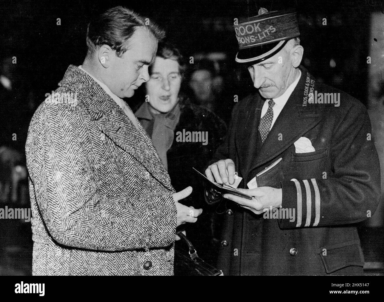 Son of Captain Scott off to Persia to Search for Red Breasted Geese - Mr. Peter Scott having his passport checked as he left Victoria. With him is his mother, Lady Kennet. Mr. Peter Scott, son of Captain Scott, the Polar explorer, left Victoria Station, London on his way to Persia and the Caspian Sea. He is in search of Red-breasted Geese, a rare species. He hopes to capture some specimens and bring them home to add to his collection of wild birds at his lighthouse home on the east coast. December 02, 1937. (Photo by Planet News Ltd.). Stock Photo