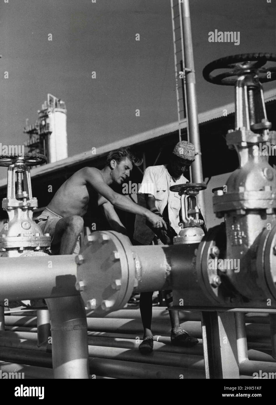 Oil Men At Work. John W. Fairbairn from Durham England, one of the English technicians employed on the Aden Oil Refinery project, see instructing an Arab worker in pipe fitting. From a barren waste christened 'Dead Man's Gulch' by the first oil men on the spot, a vast community has sprung up around the gigantic Aden Oil Refinery, which is being built to help to replace Abadan. This £45,000,000 project, which will swing into action in August, is four months ahead of target - a remarkable feat. July 1, 1954. (Photo by Fox Photos). Stock Photo