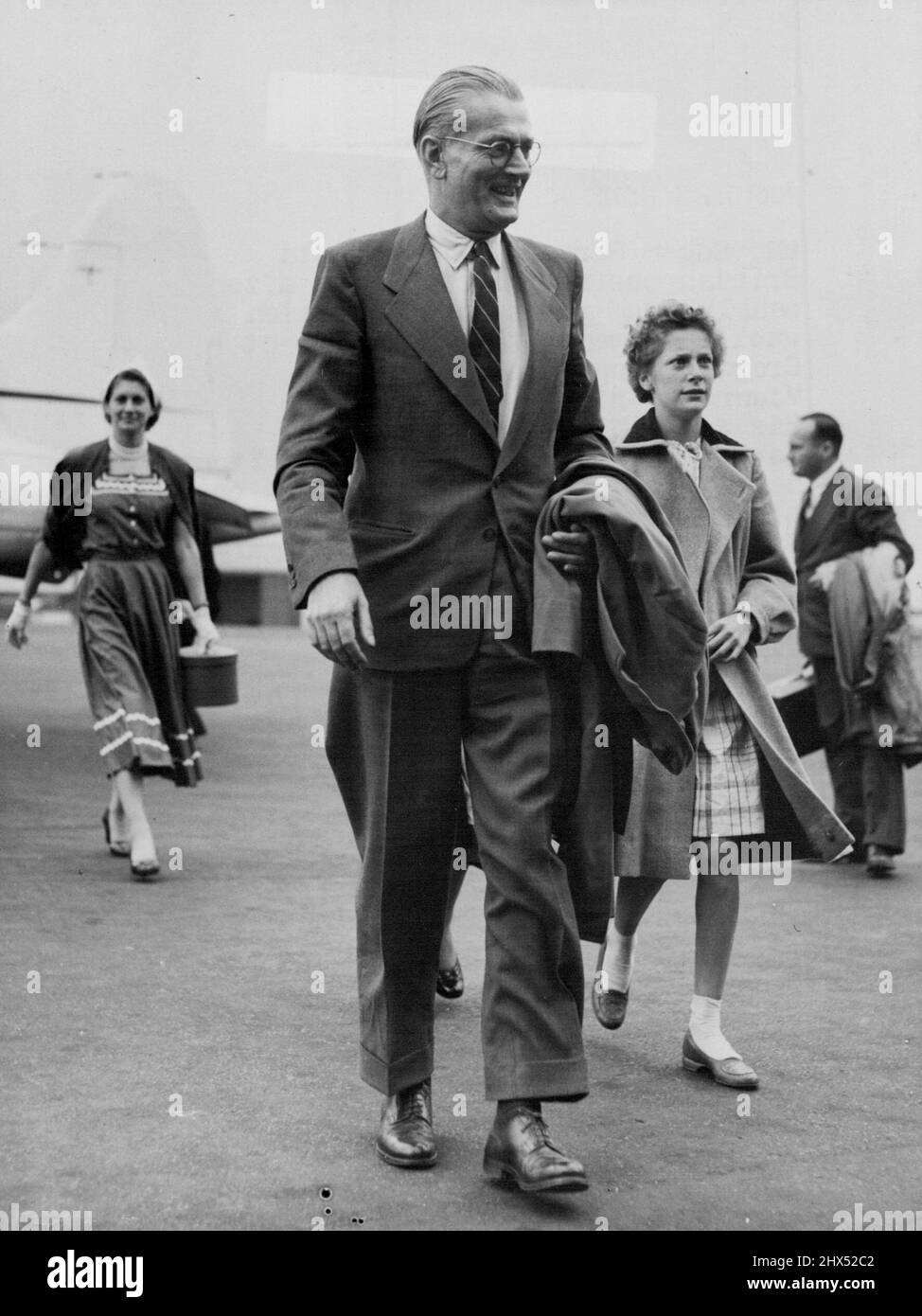 Sanders Home -- Mr. Edgar Sanders and his daughter, Denise, 13, walking from the plane at Croydon to-night. Mr. Edgar Sanders, 48-year-old British businessman released after nearly four years in a Hungarian gaol, arrived with his family at Croydon Airport, Surrey, from Vienna to-night (Thursday). His wife, Winifred, and three daughters, Barbara, Denise and Yvonne, had flown to Vienna to meet him on his release.Sanders, representative in Hungary of the Standard Electric Company, was given a 13-year sentence by the Hungarian Communists, who accused him of the Standard Electric Company, was given Stock Photo
