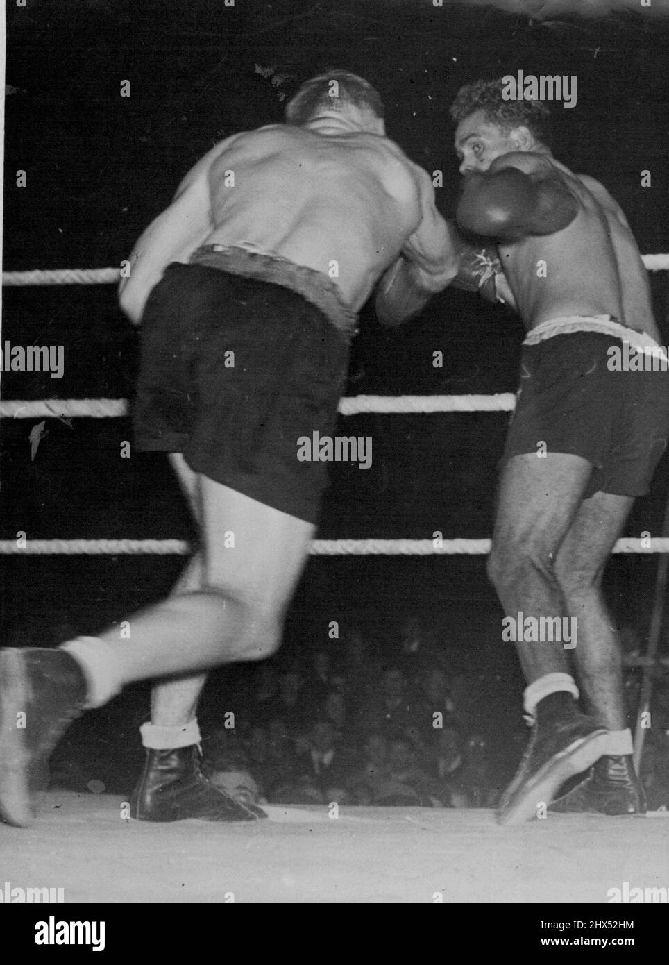 Sands V Mullett Fight At Wellington, N.Z. -- Mullett throws a solid right-hand punch, which Sands avoids by moving slightly to the left. NZ Fight. New Zealand heavyweight champion. Don Mullett, throws a solid right, which fails to connect, in his recent bout with Australian title holder Dave Sands. Sands won on points. April 10, 1948. Stock Photo