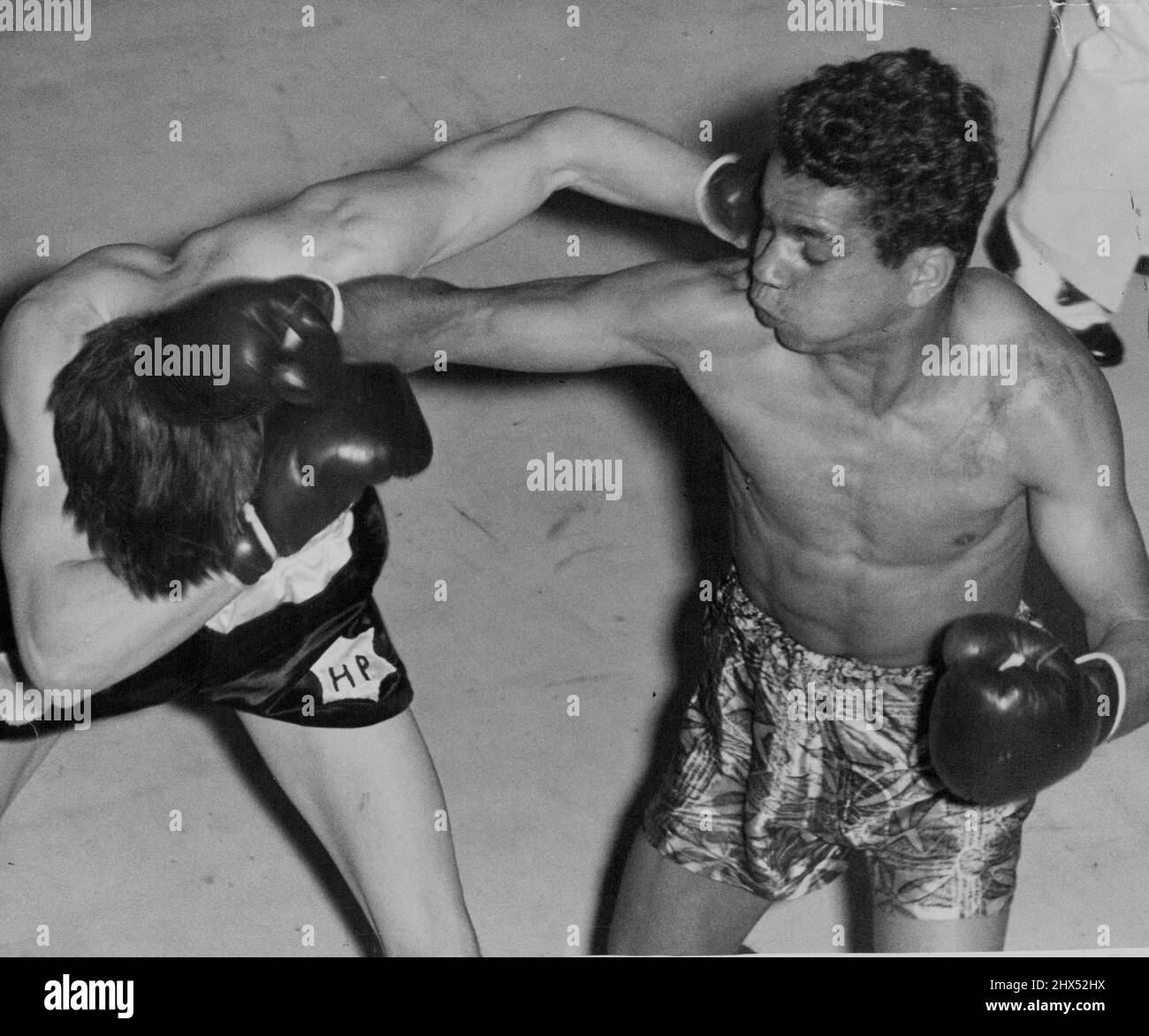 Harold Piper ducks under a right from Russell Sands in their fight at the Stadium last night. At the same time Piper lands a left on his opponent's head. Sands won a tough battle on points. October 06, 1954. Stock Photo